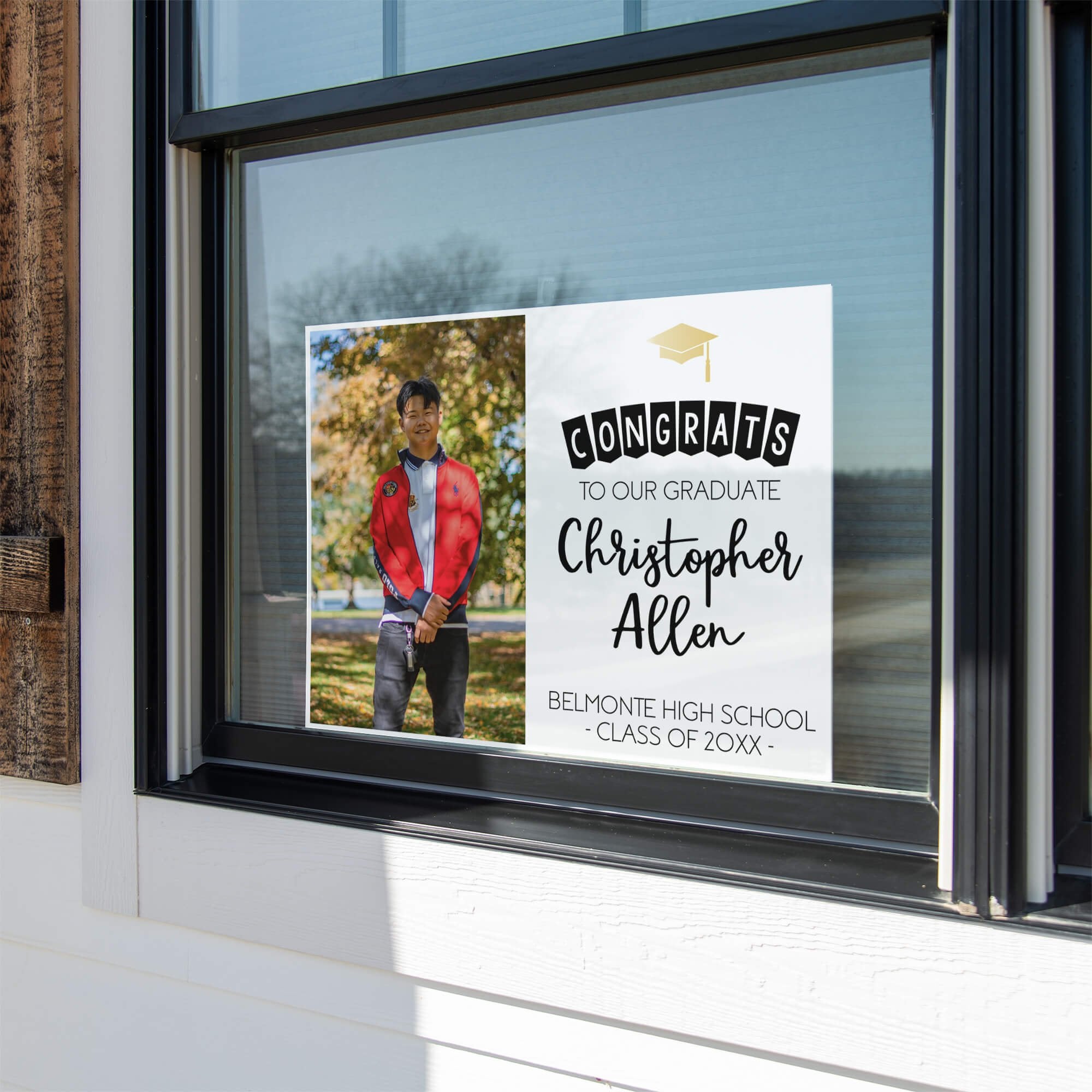 Graduation photo yard sign displayed in a window