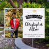 Graduation photo yard sign displayed next to pavement