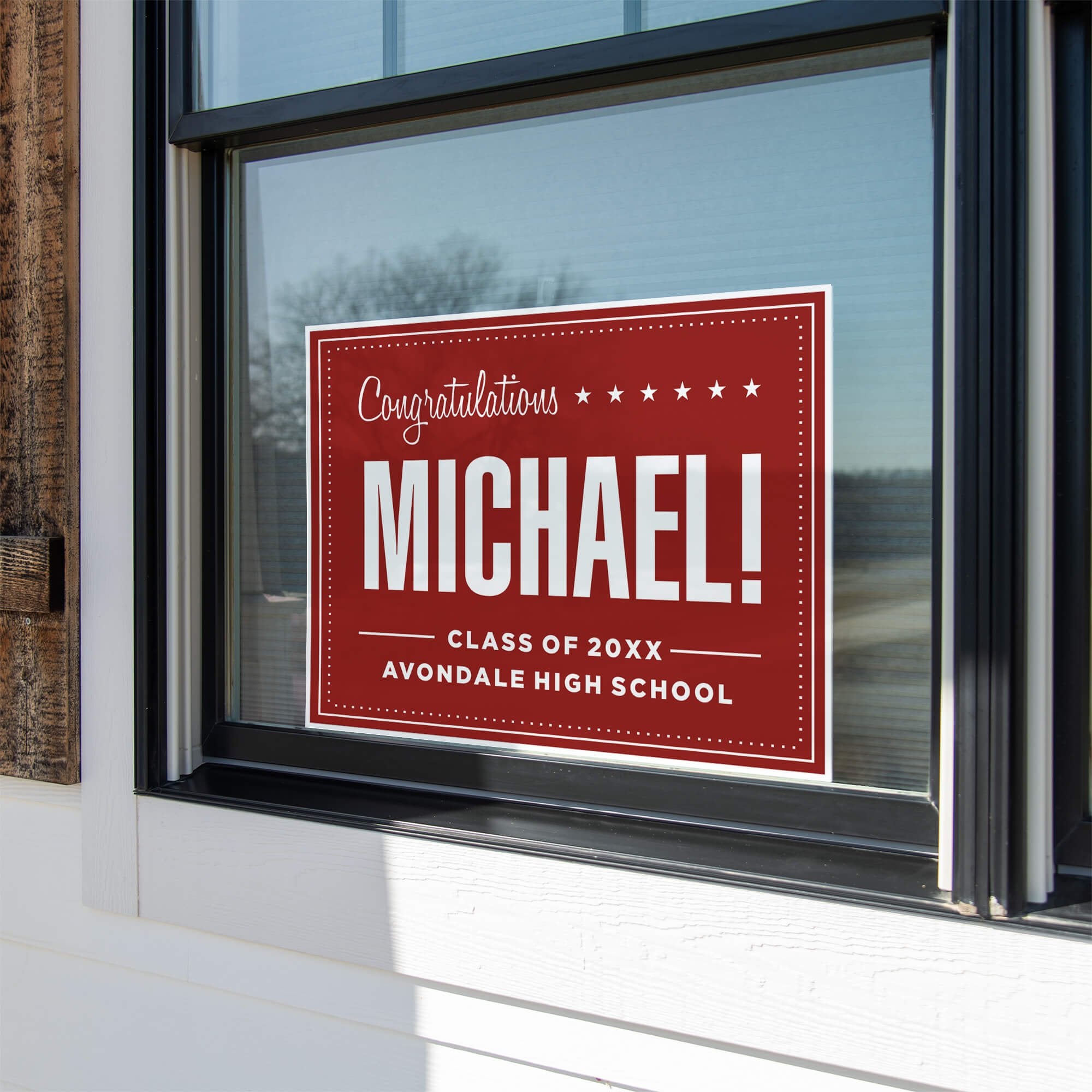 Bold name graduation yard sign displayed in a window