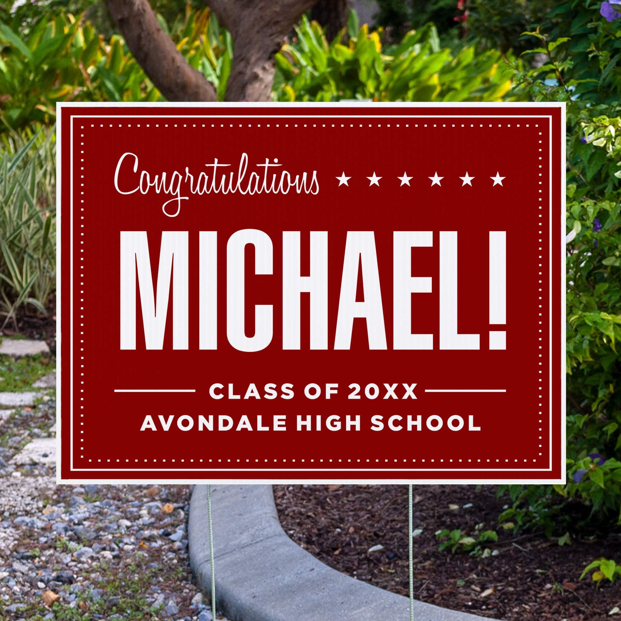Bold name graduation yard sign displayed by pavement