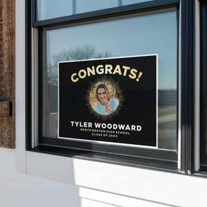 Sunburst graduation yard sign displayed in a window