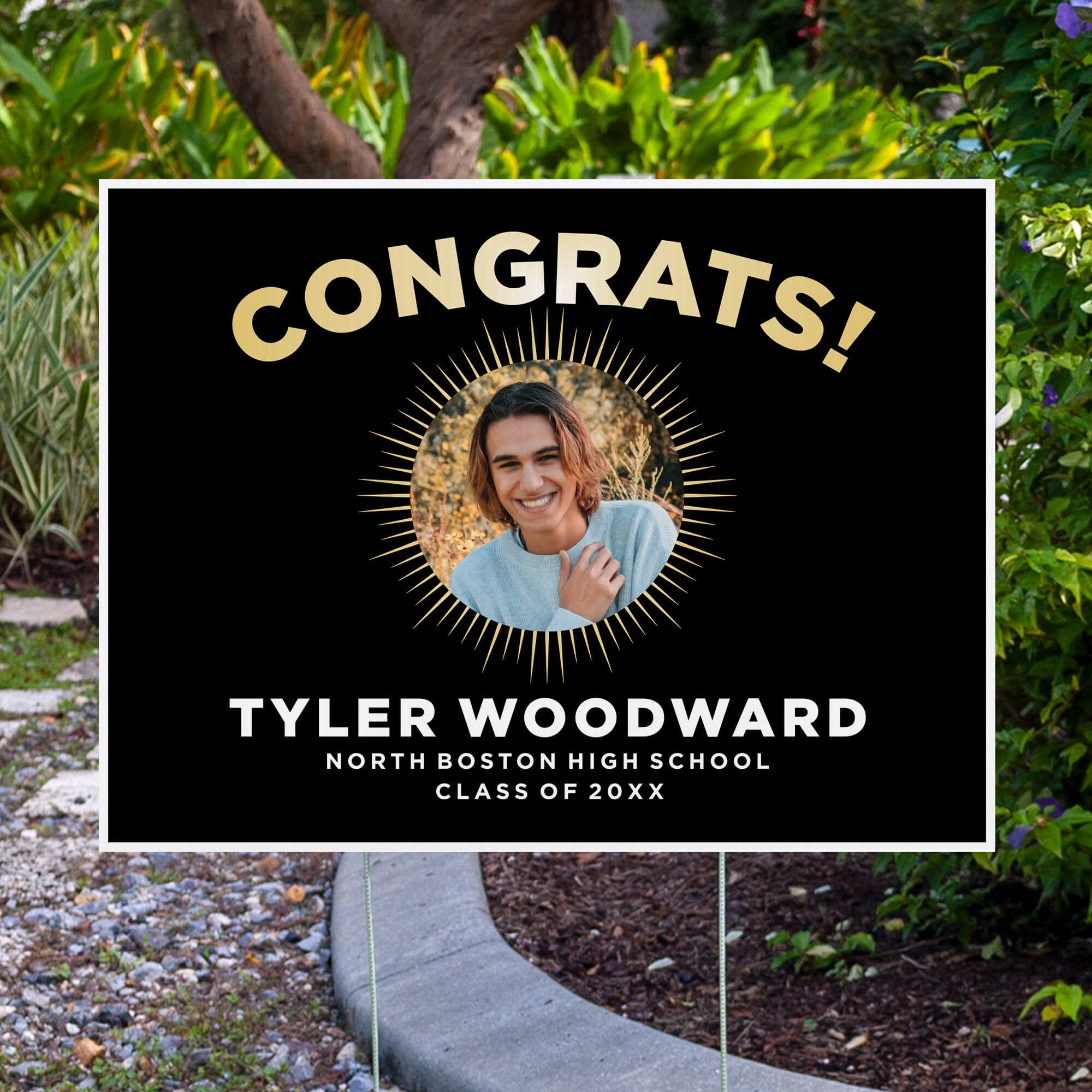 Sunburst graduation yard sign displayed next to pavement