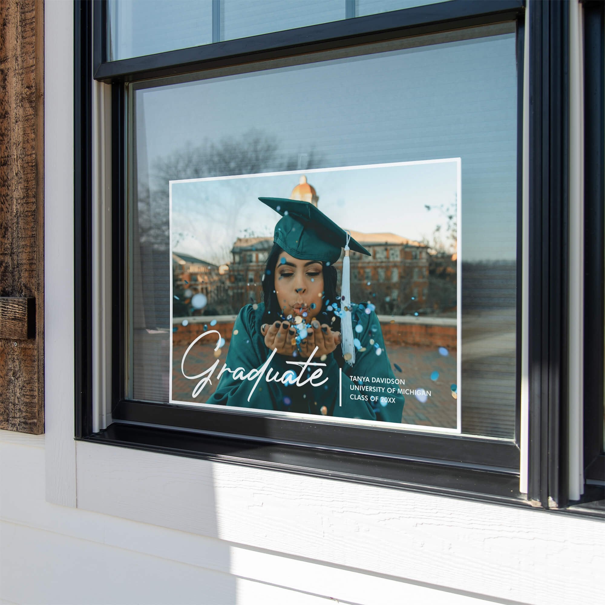 Full photo graduation yard sign displayed in a window