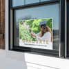 Gold text graduation yard sign displayed in a window