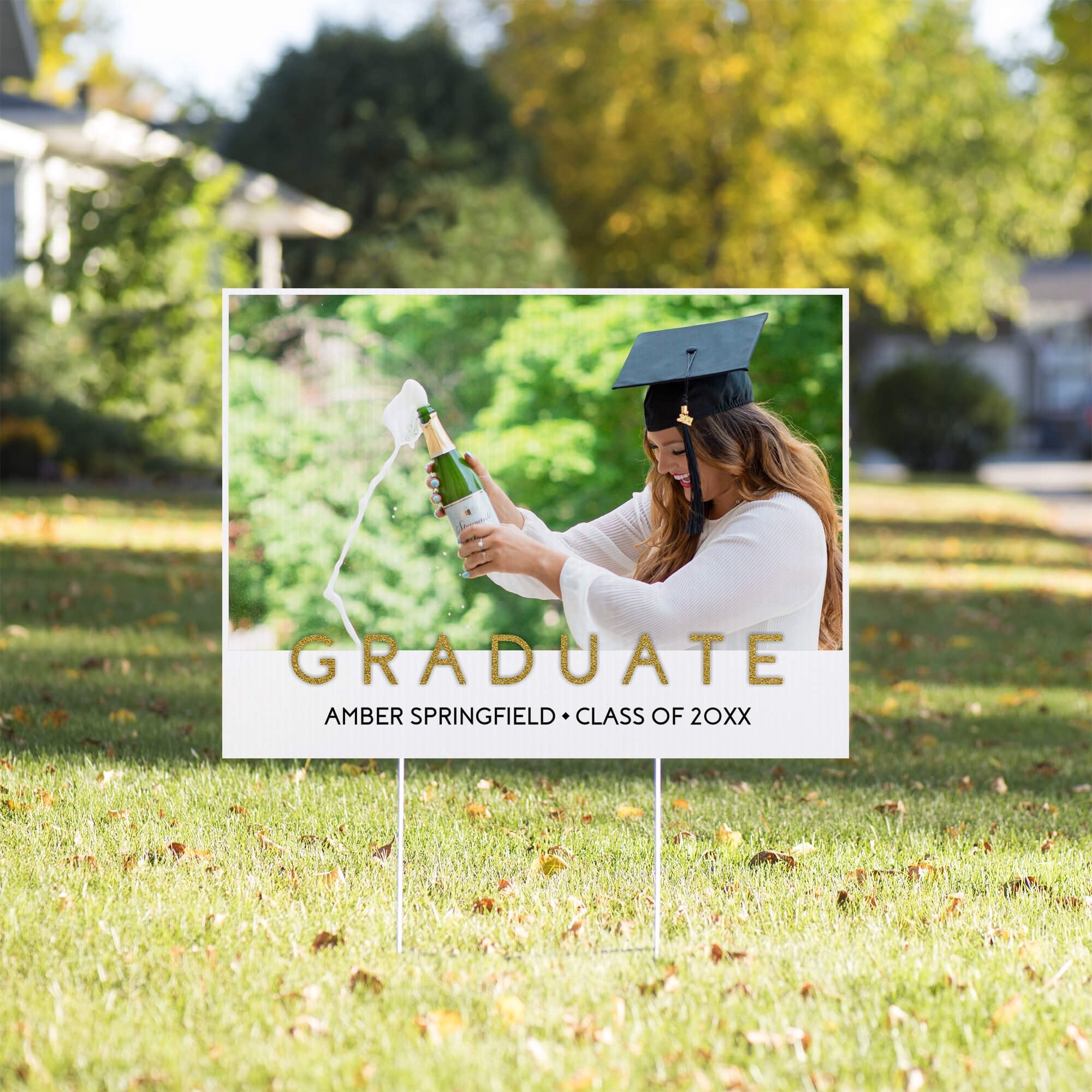 Gold text graduation yard sign displayed on a sunny yard