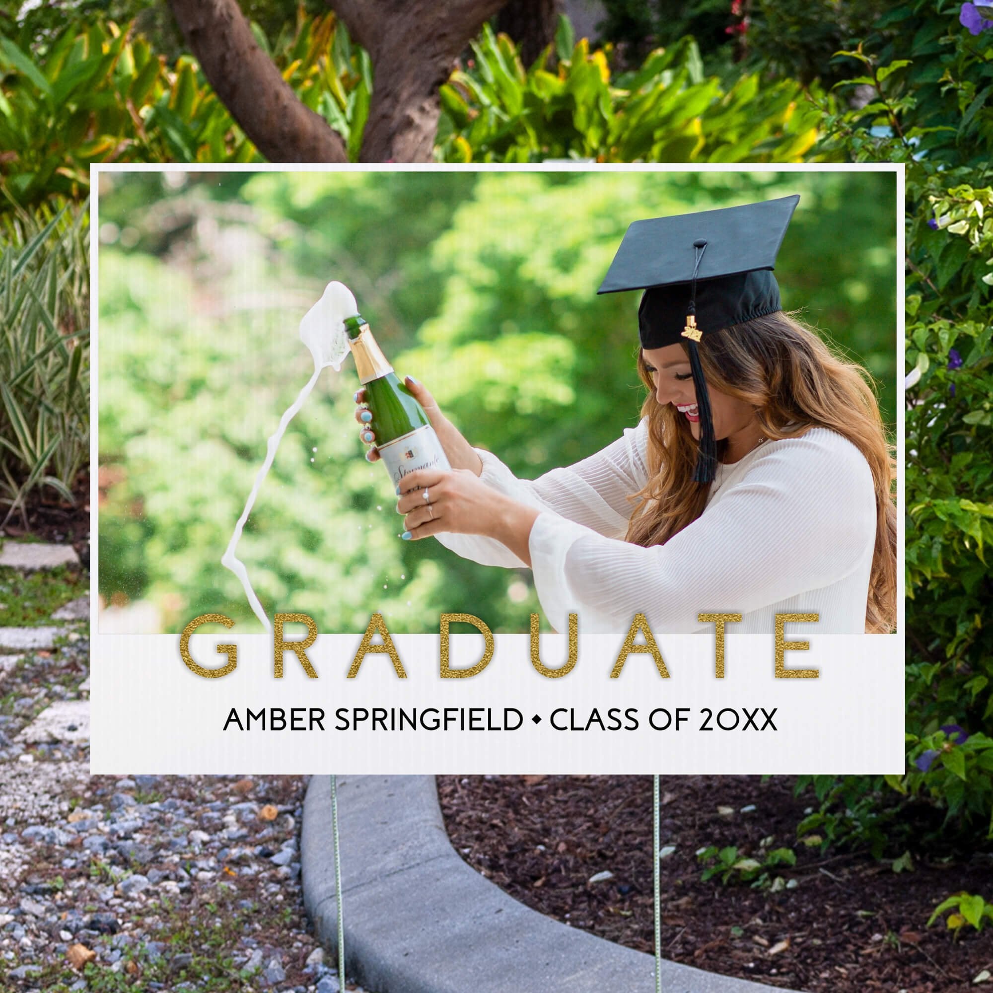 Gold text graduation yard sign displayed next to pavement