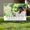 Gold text graduation yard sign displayed in a front yard