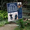 Three Photos Graduation Yard Sign displayed by a pathway leading to stairs