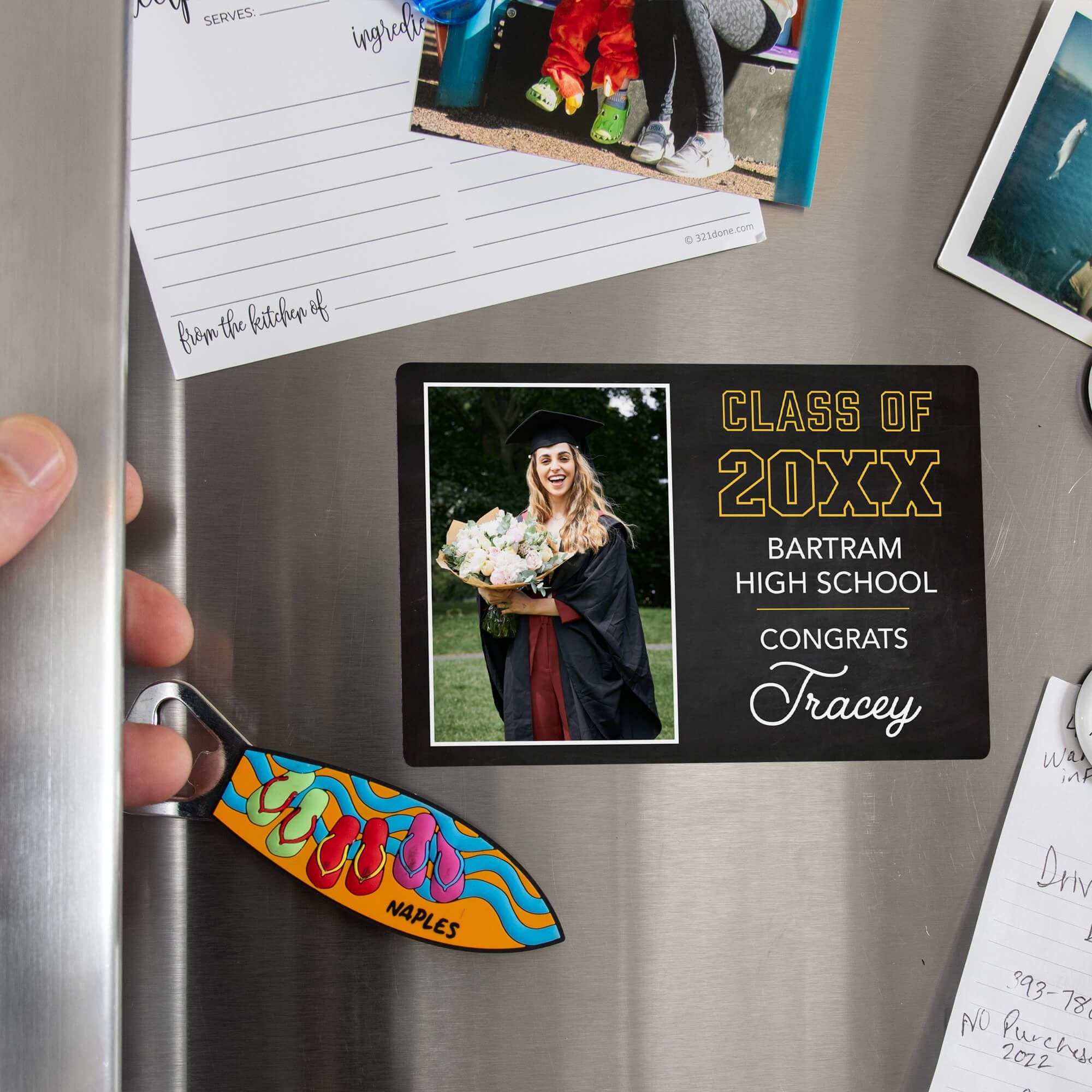 Hand placing a custom Chalkboard Design Graduation Announcement photo magnet on a stainless steel refrigerator