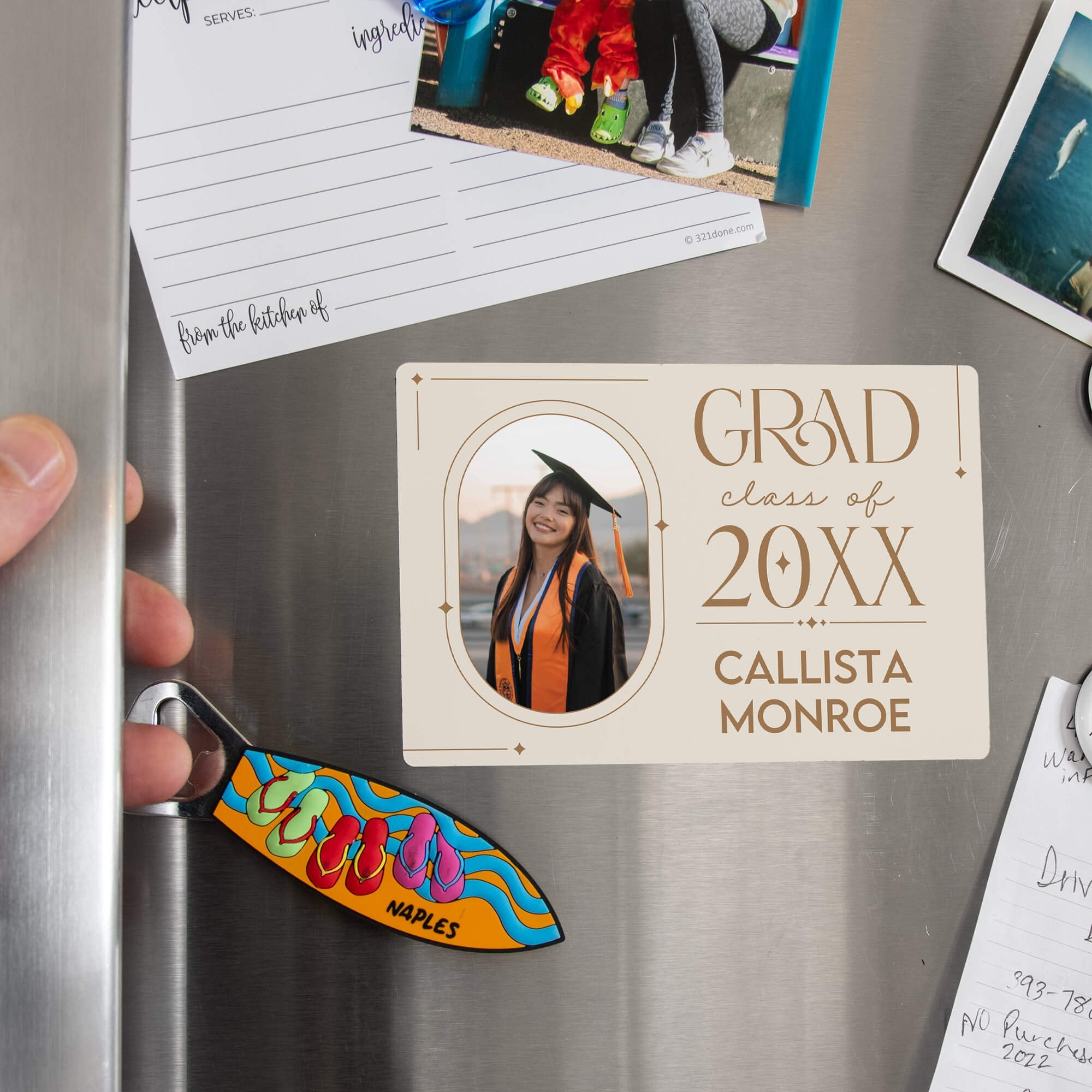 Hand placing a Modern Minimalist Graduation Announcement photo magnet on a stainless steel refrigerator