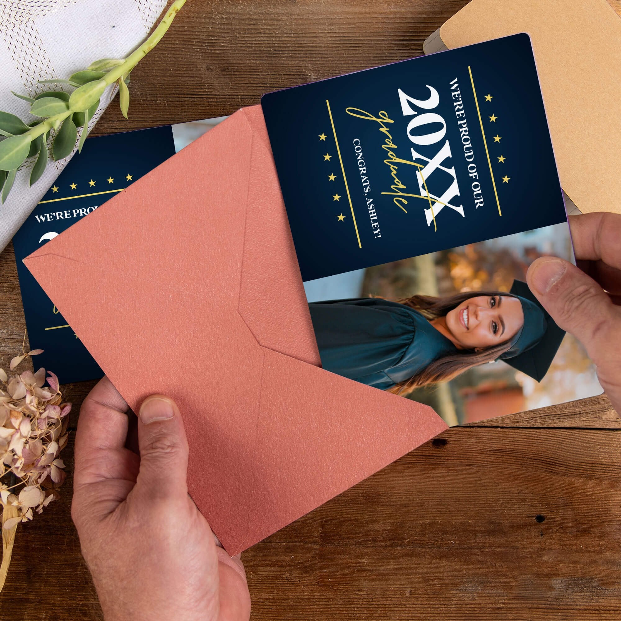 Personalized graduation photo magnet being placed into a rose colored envelope