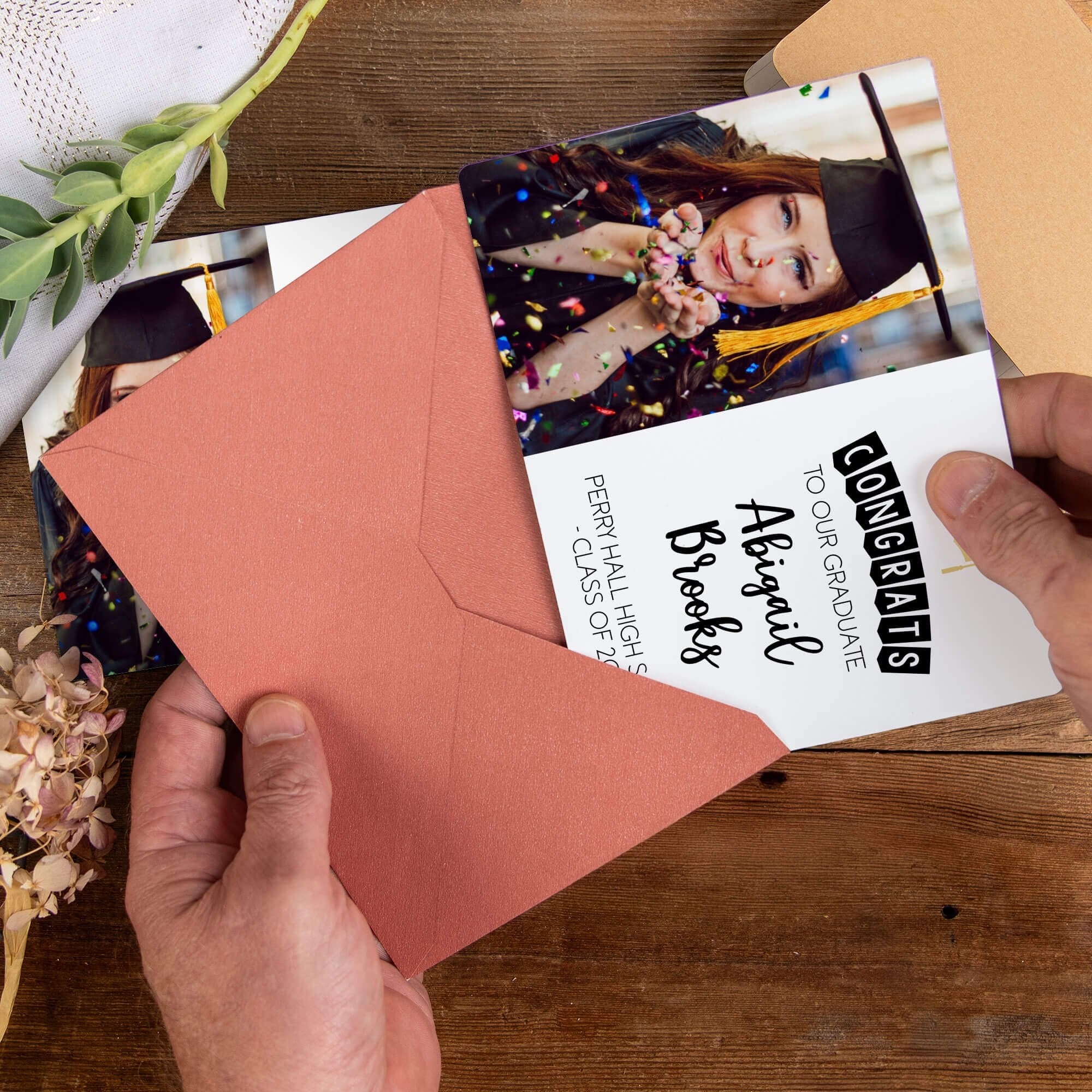Personalized graduation photo magnet being placed into a rose colored envelope
