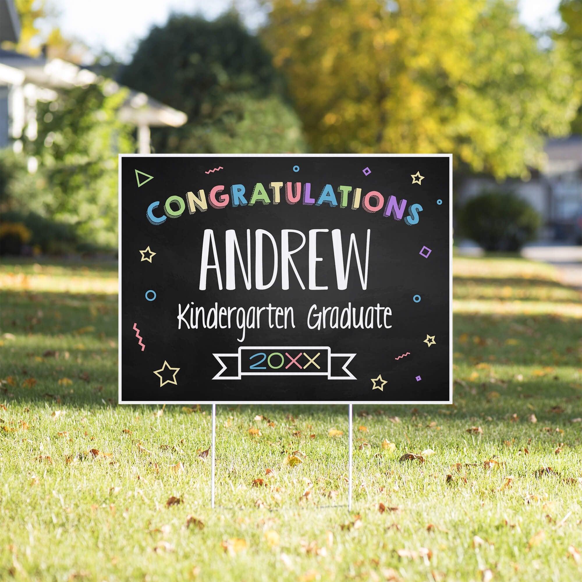 Colorful kindergarten graduation yard sign displayed in a sunny yard