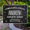 Colorful kindergarten graduation yard sign displayed next to pavement