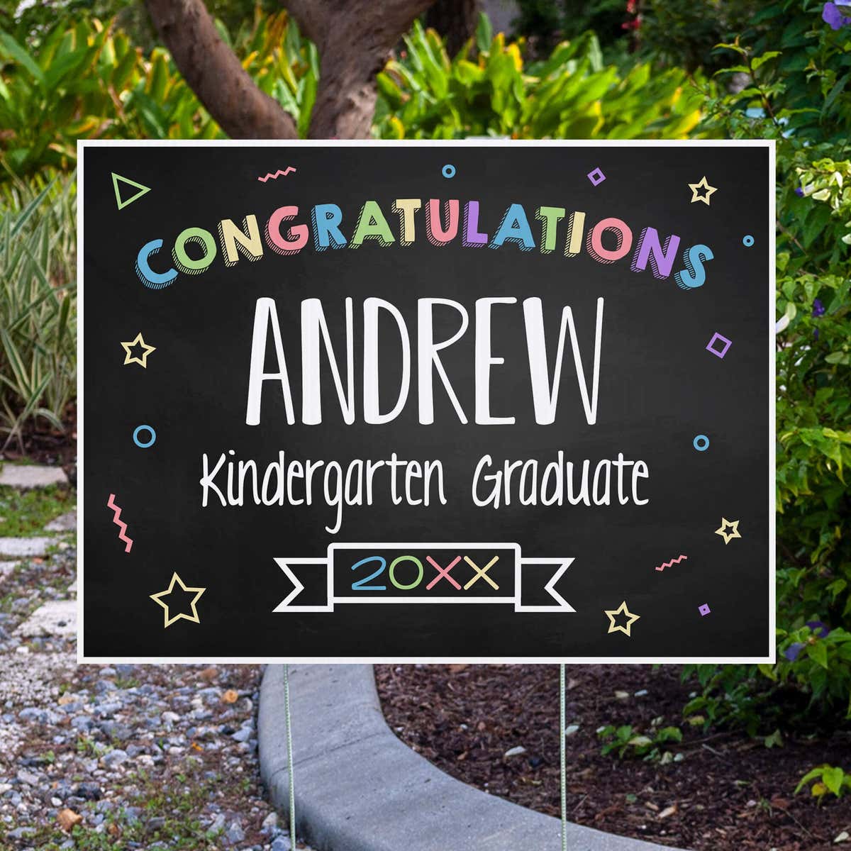 Colorful kindergarten graduation yard sign displayed next to pavement
