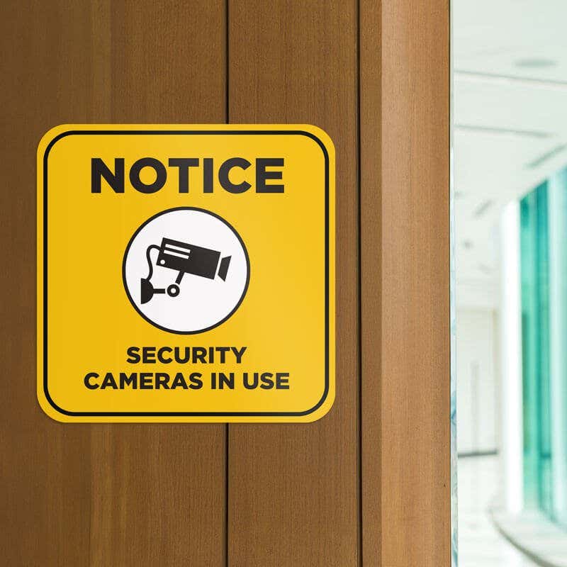 Yellow background custom sign with bold black text reads Notice security cameras in use and has surveillance camera icon