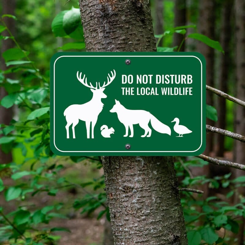 Forest green outdoor sign reads, Do Not Disturb the Local Wildlife, with images of a deer, fox, duck, and squirrel