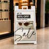 Beige sale A-frame sidewalk sign displayed in front of a shop