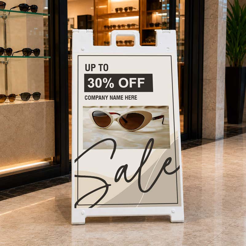 Beige sale A-frame sidewalk sign displayed in front of a shop