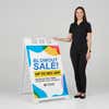 Woman standing beside a blowout sale A-frame sign for scale