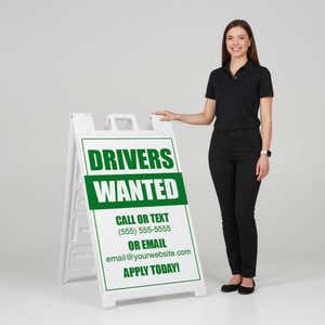 Woman standing beside a drivers wanted A-frame sign for scale