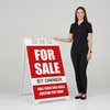 Woman standing beside a red for sale A-frame sign for scale
