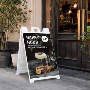 Happy hour A-frame sidewalk sign displayed in front of a store