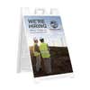Construction now hiring A-frame sidewalk sign in white plastic frame, angled view