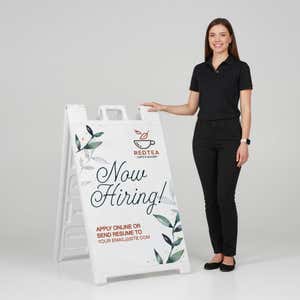 Woman standing beside a floral now hiring A-frame sign for scale