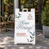 Floral now hiring A-frame sidewalk sign displayed in front of a store