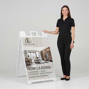 Woman standing beside a now leasing A-frame sign for scale