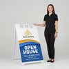 Woman standing beside a wave open house A-frame sign for scale