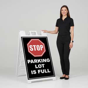 Woman standing beside a parking lot full A-frame sign for scale