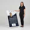 Woman standing beside a diagonal real estate A-frame sign for scale