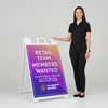 Woman standing beside a retail sale A-frame sign for scale