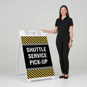 Woman standing beside a shuttle service A-frame sign for scale
