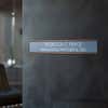 A gray name plate with a rose gold aluminum holder by an office