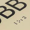 A close-up on the braille and tactile text on the ADA sign