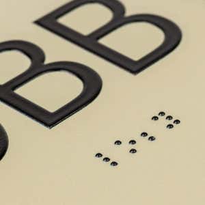 A close-up on the braille and tactile text on the ADA sign