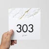 A person holding a modern arch 2-layer sign with a room number on it