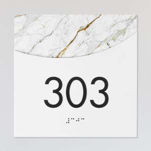 A layered ADA sign for a room number with a white foreground and the white marble background
