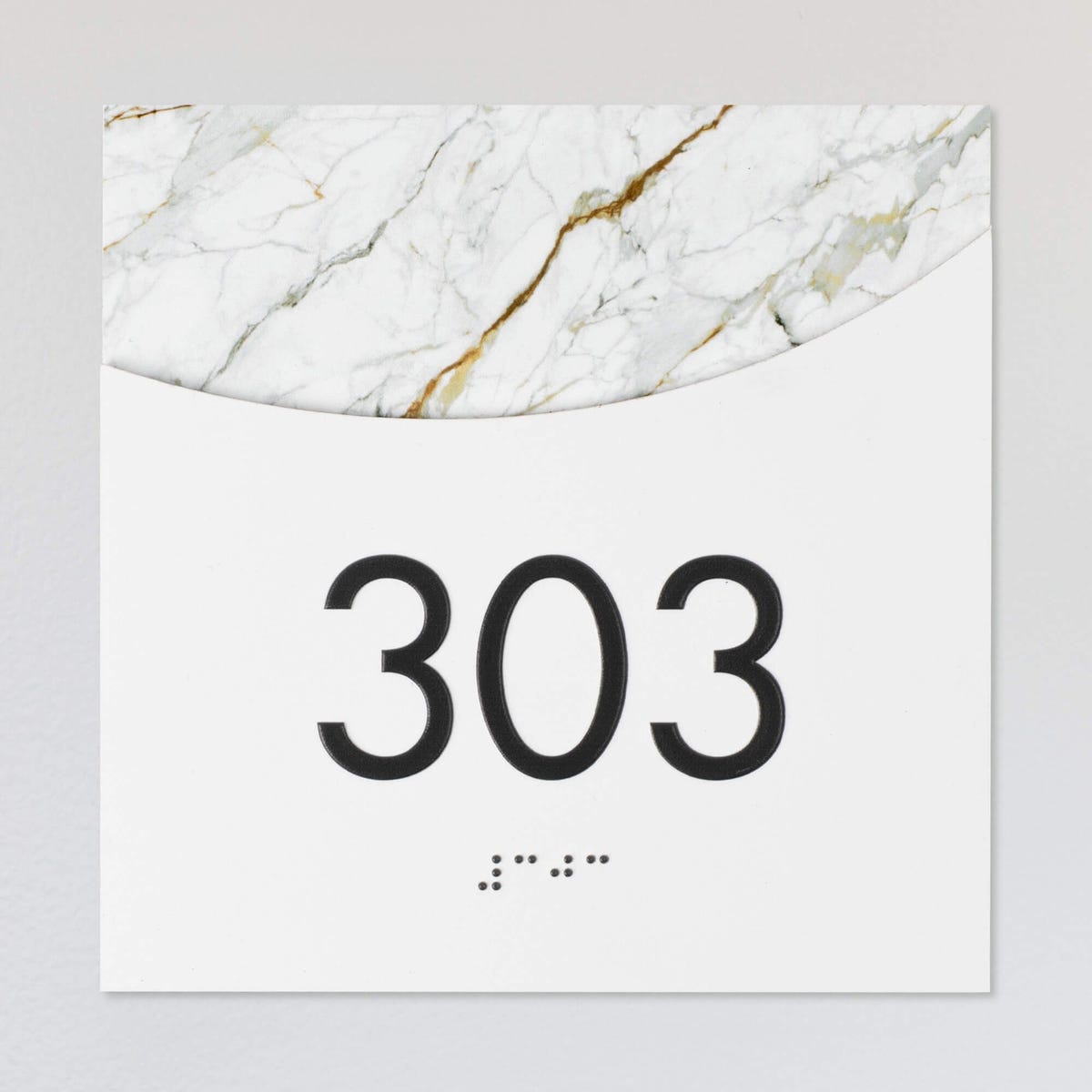 A layered ADA sign for a room number with a white foreground and the white marble background