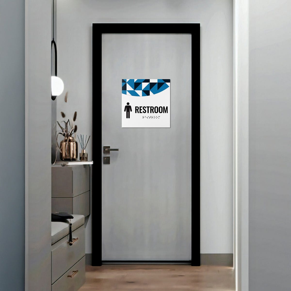 A 2-layered ADA sign for a restroom with a white foreground and a blue geometric background