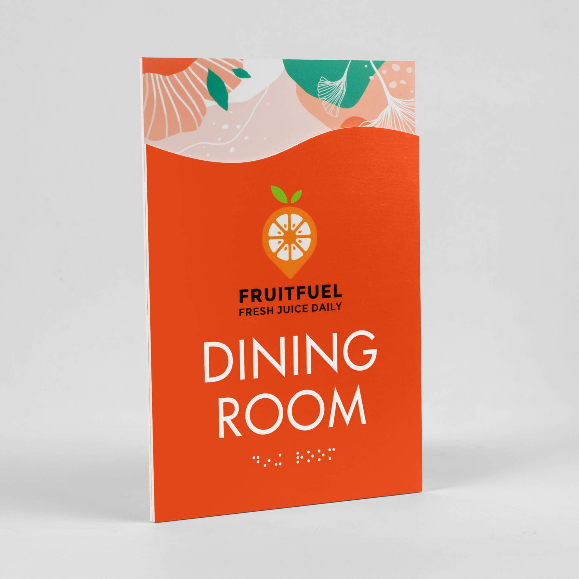 A 2-layer ADA sign for a dining room with an orange foreground and orange floral background sitting at an angle A 2-layer ADA sign for a dining room with an orange foreground and orange floral background sitting at an angle