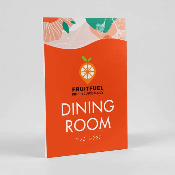 A 2-layer ADA sign for a dining room with an orange foreground and orange floral background sitting at an angle