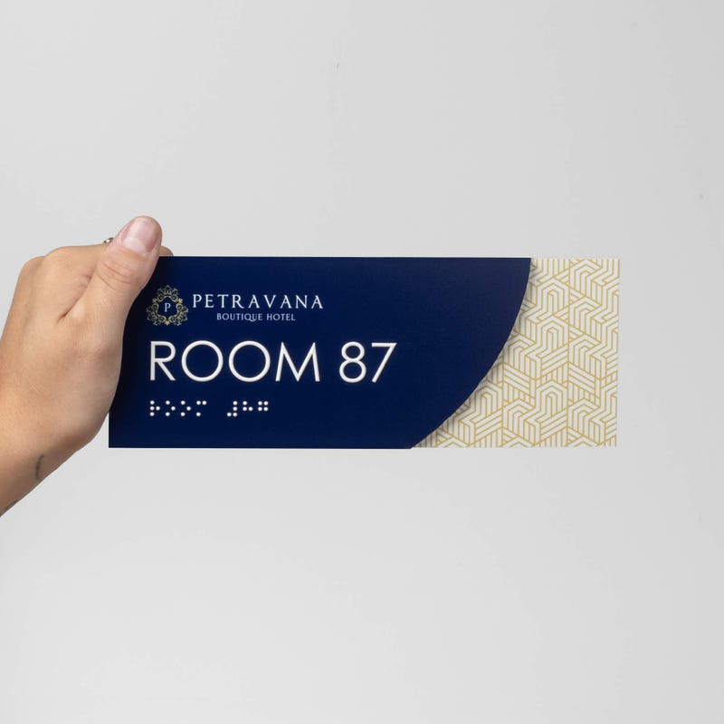 A person holding the modern sleek 2-layered ADA sign
