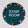 The custom round 2-layered ADA sign hanging on a wall for an exam room