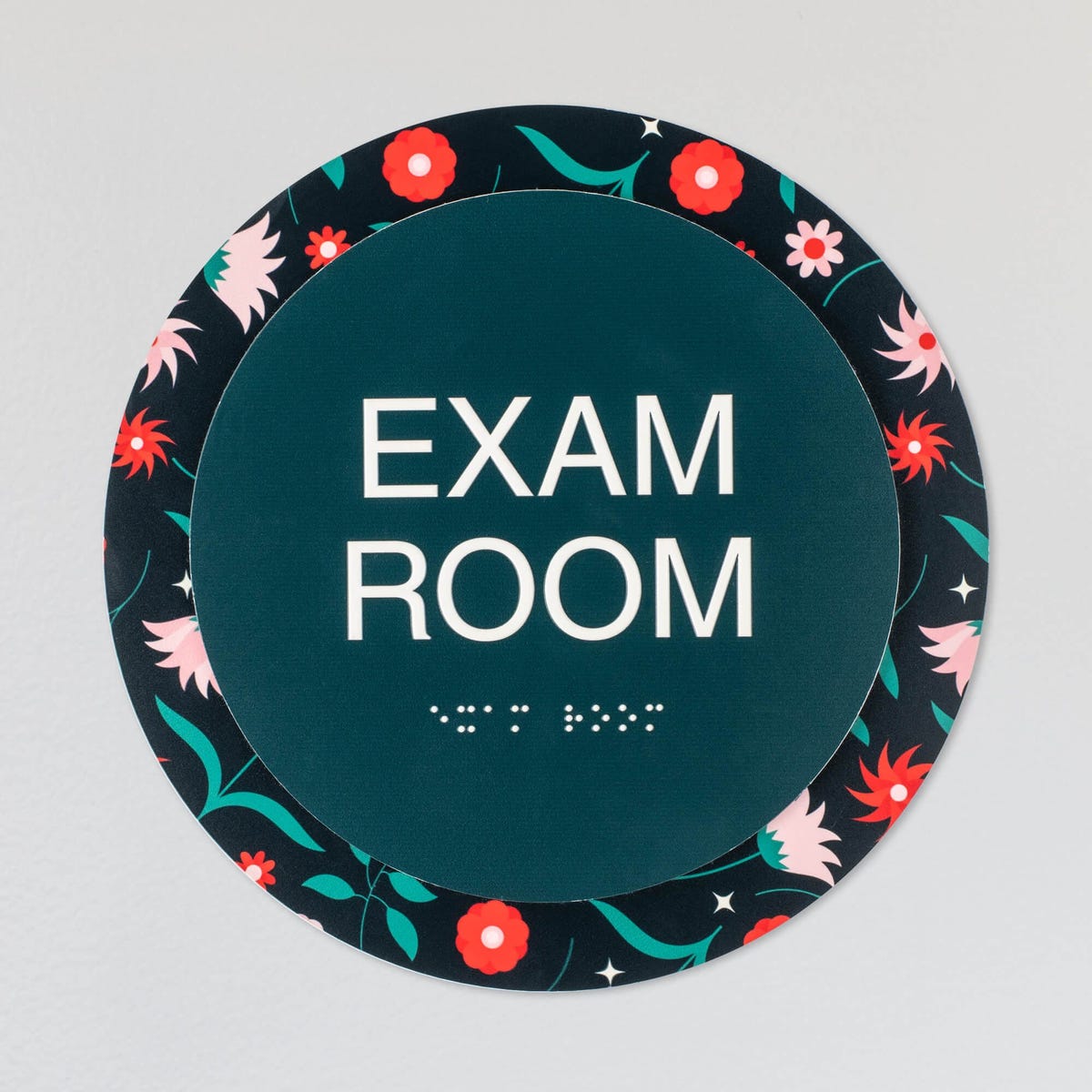 The custom round 2-layered ADA sign hanging on a wall for an exam room