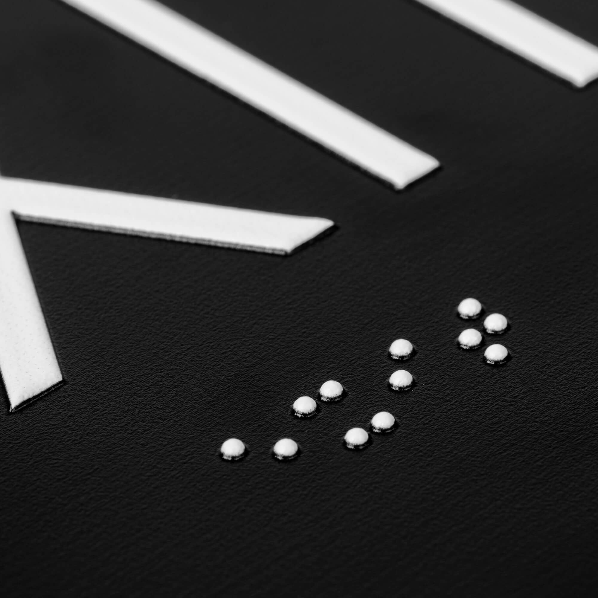 A close-up on the braille and tactile text on the ADA sign