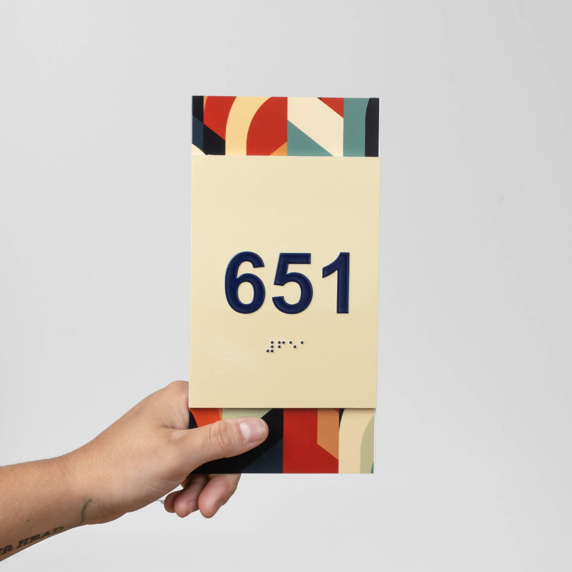 A person holding a modern vertical 2-layer sign with a room number on it